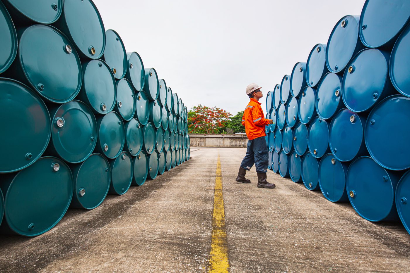 Construction worker inspecting stack of chemical barrels
